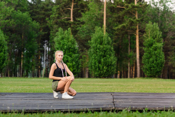 Young female stretching before fitness training session at the park. Healthy young woman warming up outdoors. She is stretching her arms and looking away,hi key.