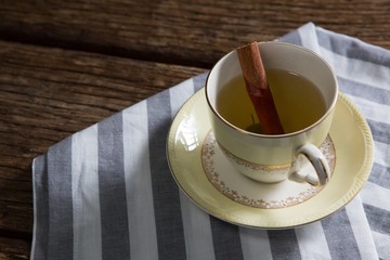 Cup of tea with cinnamon stick on napkin