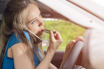 frivolous woman driving the car, painting her lips and talking on the phone