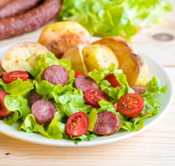 Smoked sausage with vegetables salad on a wooden board