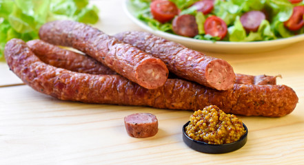 Smoked sausage with vegetables salad on a wooden board