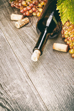 Wine bottle , grape and corks on wooden table