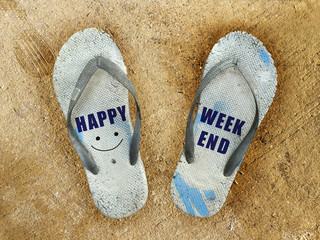 Happy weekend word and smile and old white sandal on sand background