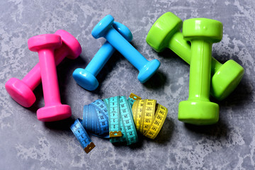 Barbells, colorful tape measures and dumbbells placed in pattern