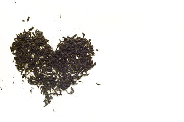 Black tea leaves scattered in the shape of a heart on  yellow b