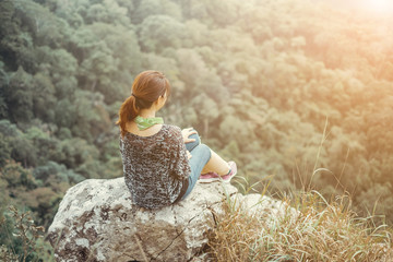 Cute girl watching the beautiful cliffside seek the forest floor.