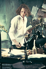 Writer at work. Handsome young writer standing near the table and making up something in his mind