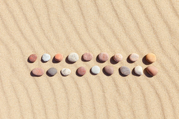 Fototapeta na wymiar Pattern of colored pebbles on clean sand. Zen background, harmony and meditation concept