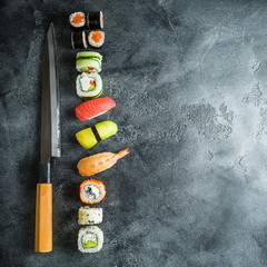 Japanese food - sushi, rolls, rice with shrimp and knife on a dark table. Flat lay, Top view © artifirsov