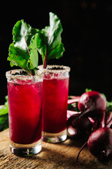 Red beet juice and gin cocktail on rustic background
