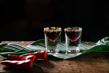 Two spicy tequila shots on rustic background