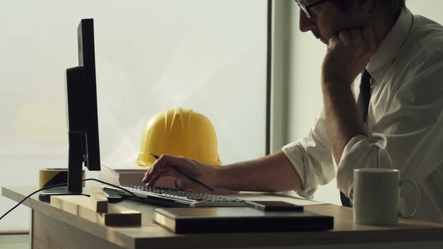 Construction engineer working on desktop computer using CAD software to sketch project in architecture studio office
