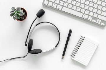 Worktable in call center. Headphones, keyboard and notebook on grey background top view