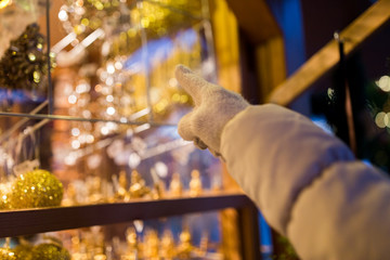 hand pointing at christmas toys behind shop window