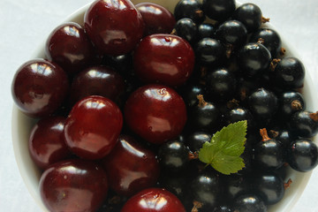 Currant berries and cherries on a white plate and white tablecloth
