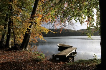 malerischer Steg mit Boot am See im Herbst