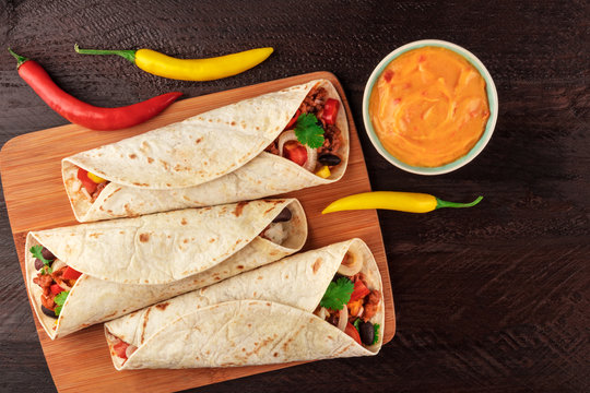 Mexican burritos with cheese salsa, chili peppers, and copyspace