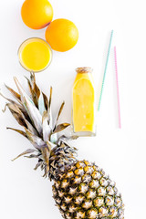 Fresh pineapple juice in glass and bottle on white background top view