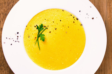 Creamy corn soup in white bowl, garnished with pepper, scallion and parsley. Vegetable soup. View from above, top studio shot, horizontal