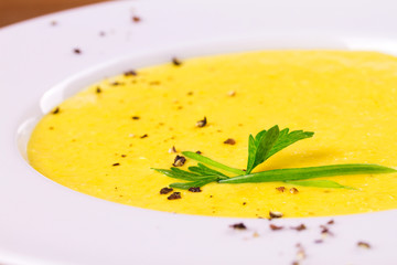 Creamy corn soup in white bowl, garnished with pepper, scallion and parsley, horizontal