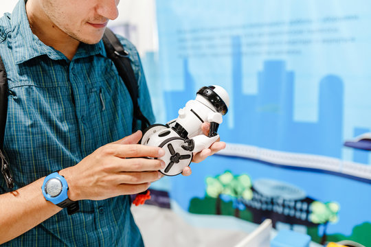 Young Man Holding Toy Robot In Hand At The Exhibition