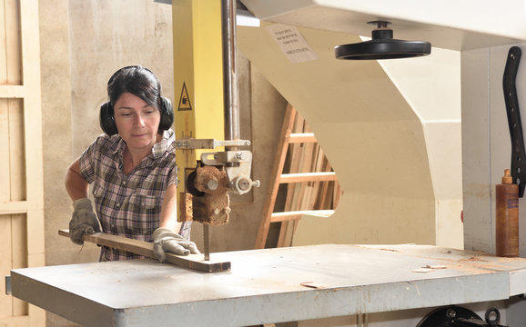 a woman working in a carpentry workshop, sawing band