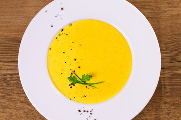 Creamy corn soup in white bowl, garnished with pepper, scallion and parsley. Vegetable soup. View from above, top studio shot, horizontal
