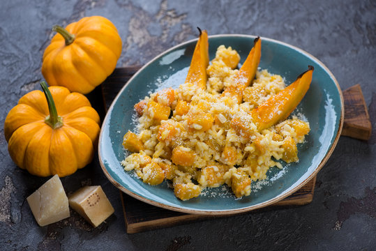 Turquoise plate with pumpkin risotto on a wooden serving board, studio shot
