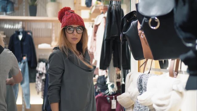 Young stylish hipster female trying on caps in the store and have fun. Shopping