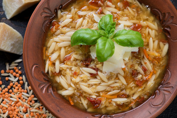 Close-up of a clay plate with lentils and pasta soup, view from above