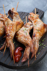 Close-up of wooden skewers with barbecued chicken wings, selective focus, studio shot