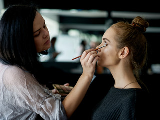Make up artist doing professional make up of young woman. 
