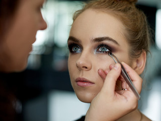 Make up artist doing professional make up of young woman. 