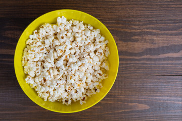 Popcorn in bowl on wooden background	
