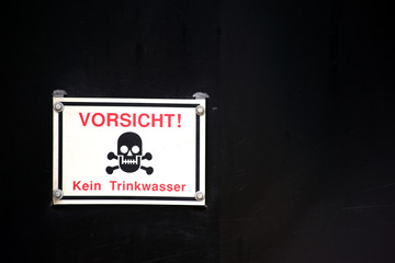 Warnschild Vorsicht kein Trinkwasser  / Ein Warnschild mit Totenkopf und roten Schriftzeichen vor...