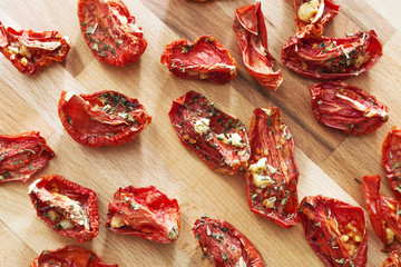 Tomatoes sun-dried in small pieces lying in wooden background.