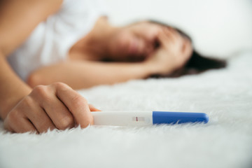Obraz na płótnie Canvas Upset woman lie sad in the bed with negative pregnancy test