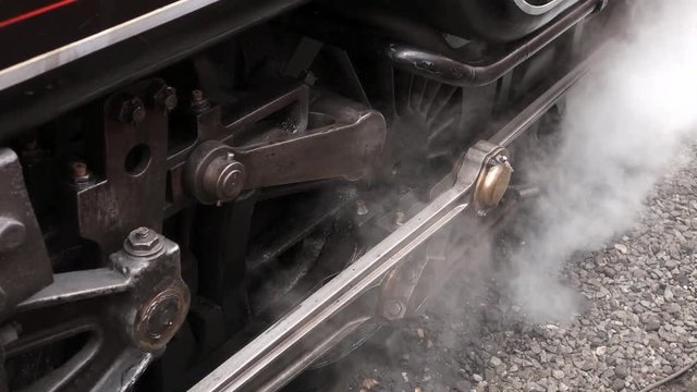 Smoking wheels, connecting rods and valve gear of a stationary steam train.