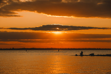 Catching A Sunset. Man fishing in last rays of sunlight on sea shore