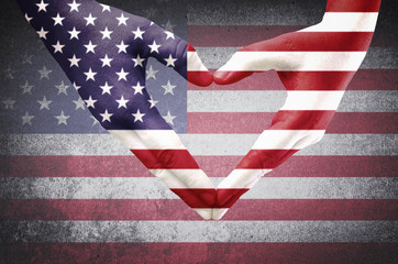 Hands of a young man forming a heart patterned with an American flag