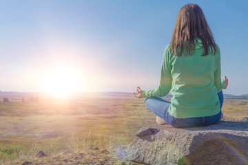 woman in yoga and meditates in the lotus position on a mountain in a magical spiral of stones