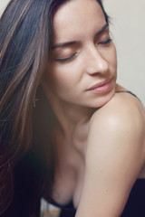 Obraz premium Close up highly-detailed picture of beautiful charming young female with perfect skin, brunette heavy long hair and closed eyes, resting indoors. Seductive lady posing in studio wall background.