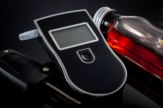 DUI And Don't Drink And Drive Concept With A Breathalyzer Next To A Bottle Of Alcohol And The Car Keys. A Breath Alcohol Analyzer Can Be Used To Test If A Person Is Capable Of Driving Or Not