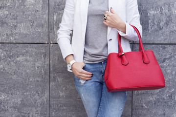 Casual woman in white jacket with red bag in hand street look