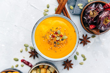 Bowl with fresh homemade carrot pumpkin soup and spices.