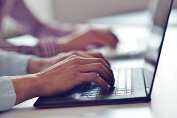 Fototapeta premium Man's hands typing on laptop keyboard