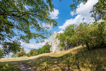 White rock in forest, national park, green trees, blue sky with clouds