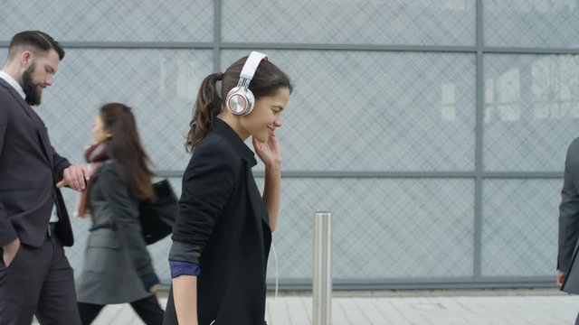  Relaxed businesswoman listening to music & dancing as she walks to work 