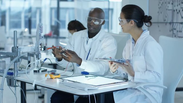  Electronics engineers working in lab building & testing electronic devices