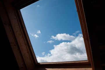 blick durch dachfenster auf freundlichen wolkenhimmel